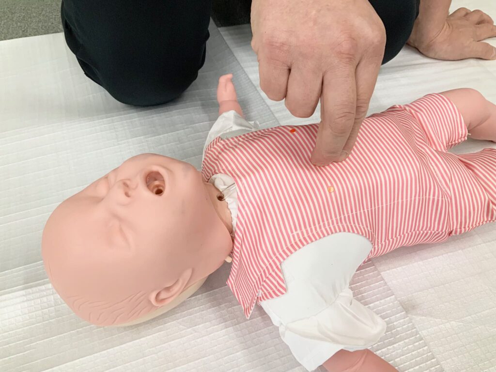 乳児の人形で心配蘇生の練習をしている